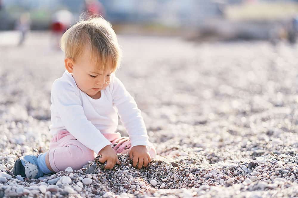 Baby playing with rocks on the beach