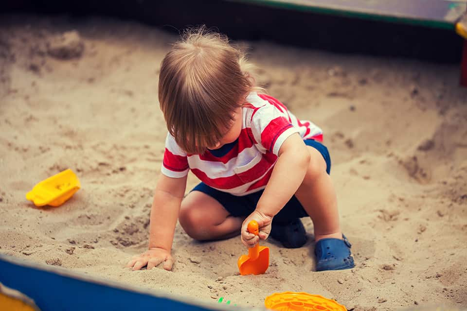 little boy playing in sandbox
