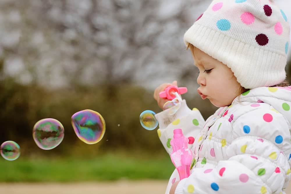 a toddler blowing bubbles