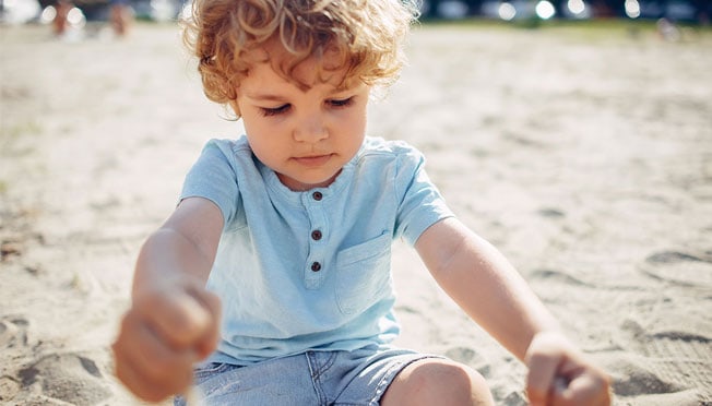 a toddler playing with sand