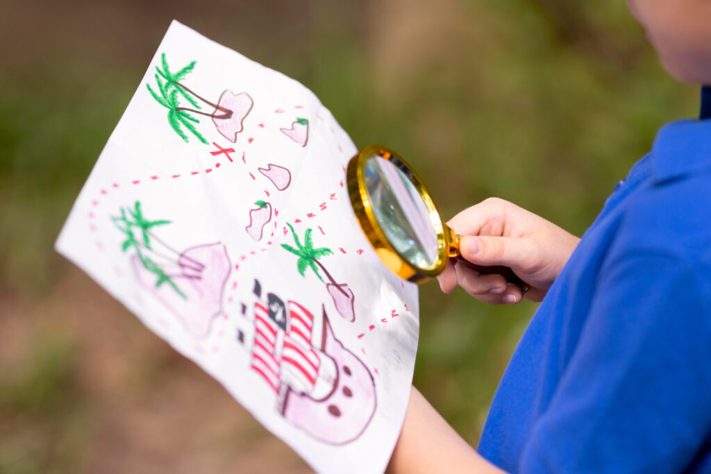 a boy using a magnifying glass looking at the map