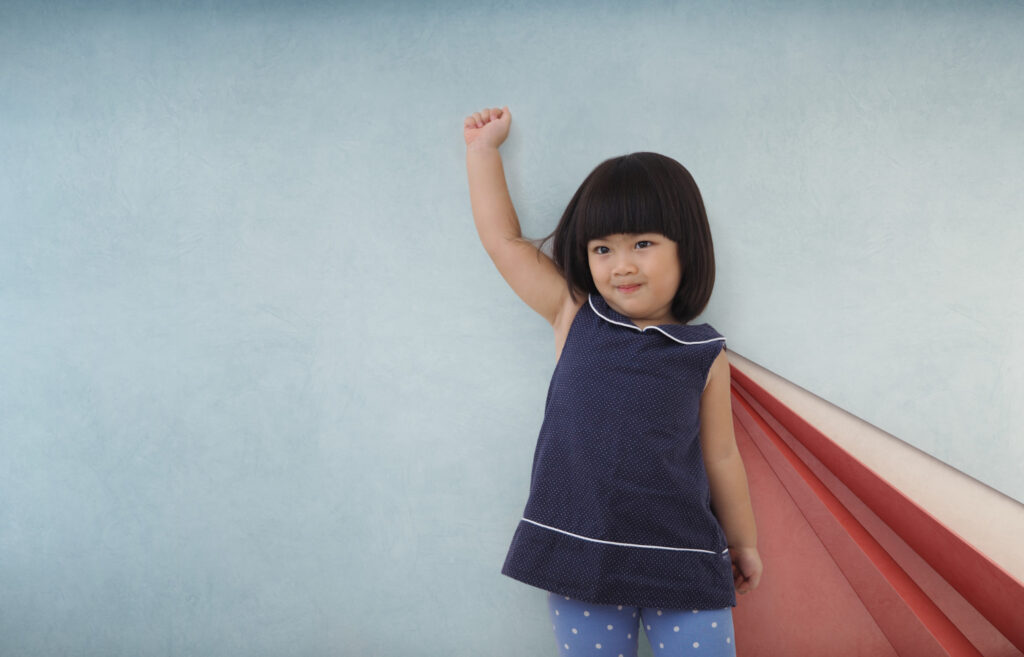 a small Asian girl posing as a super woman